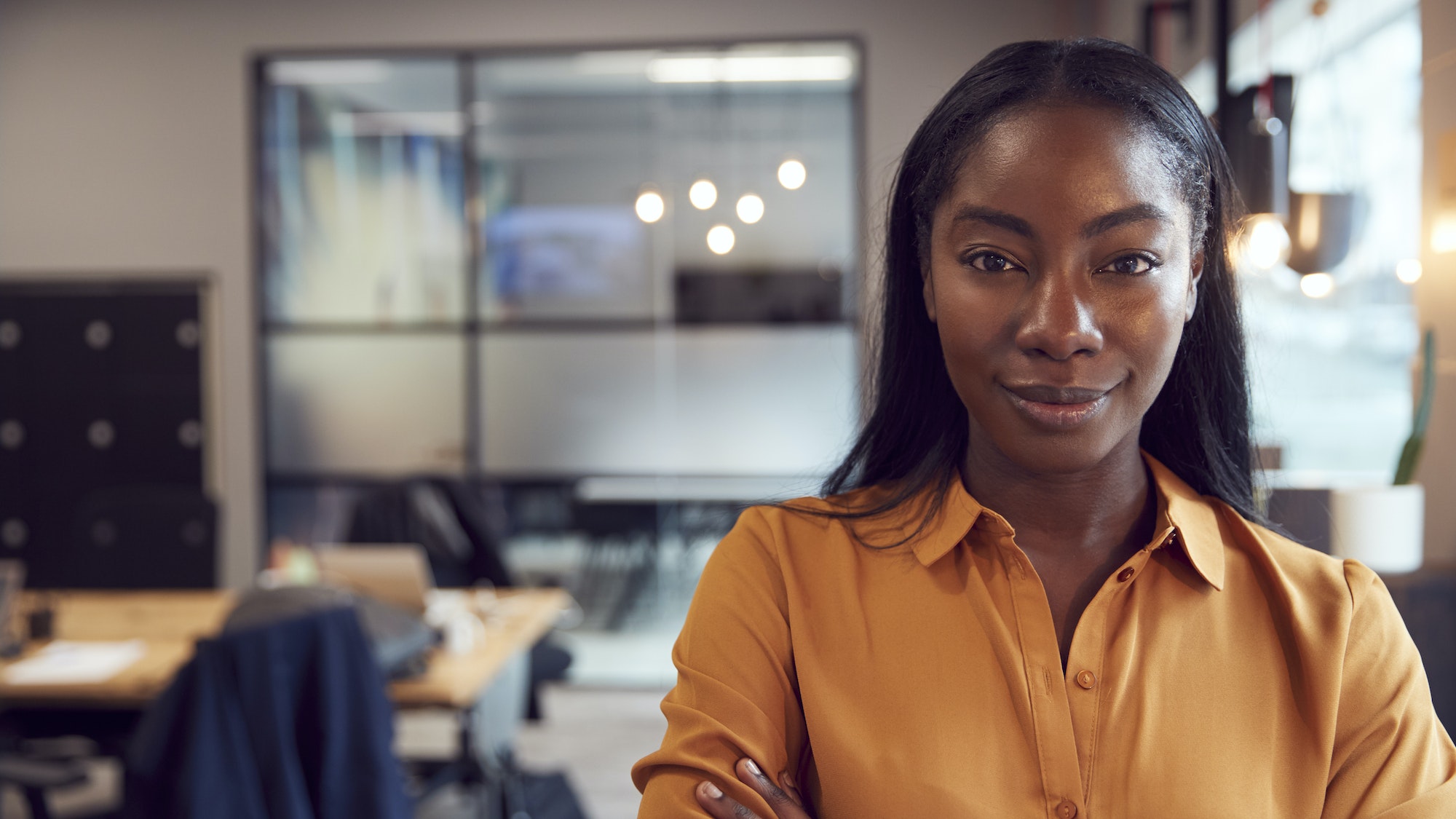 Head And Shoulders Portrait Of Smiling Young Businesswoman Working In Modern Office
