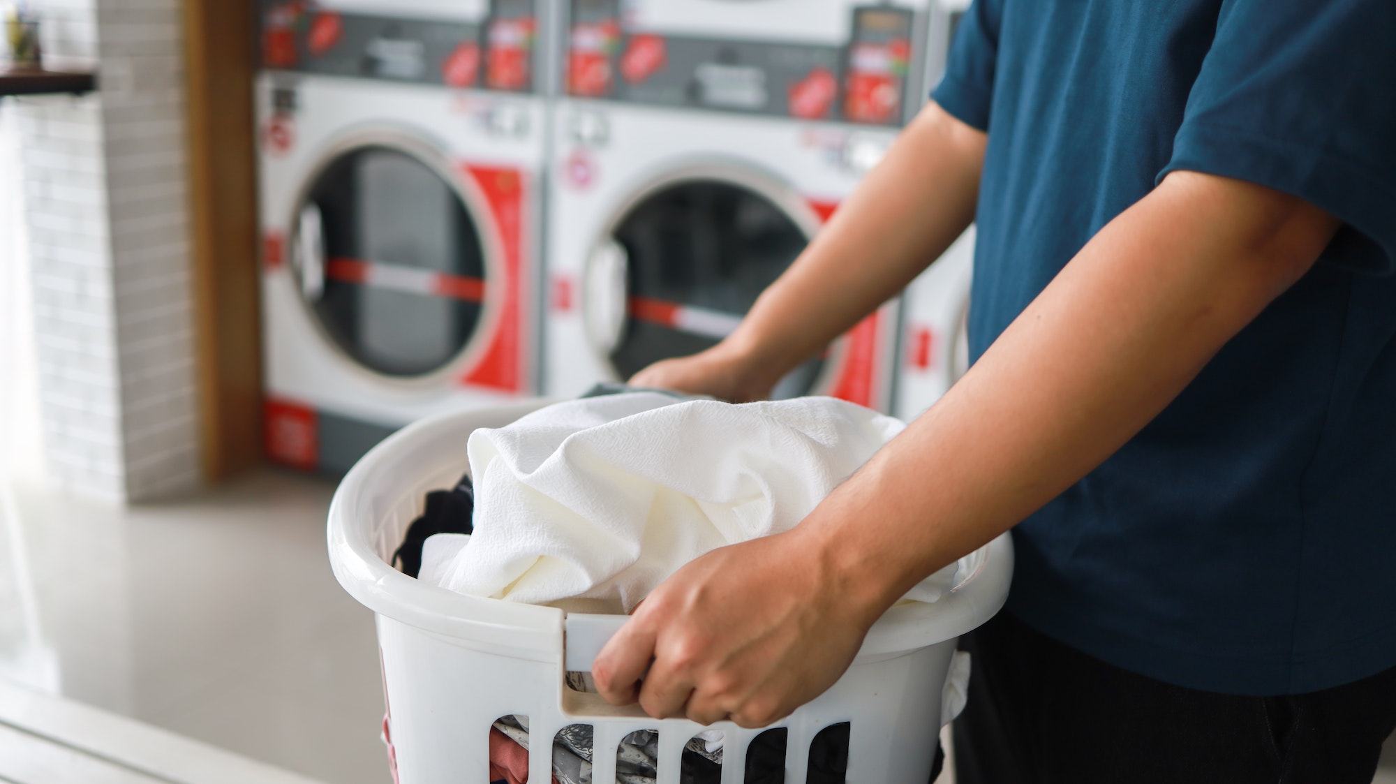House husband with Basket and dirty laundry washed clothing in laundry room interior. washing