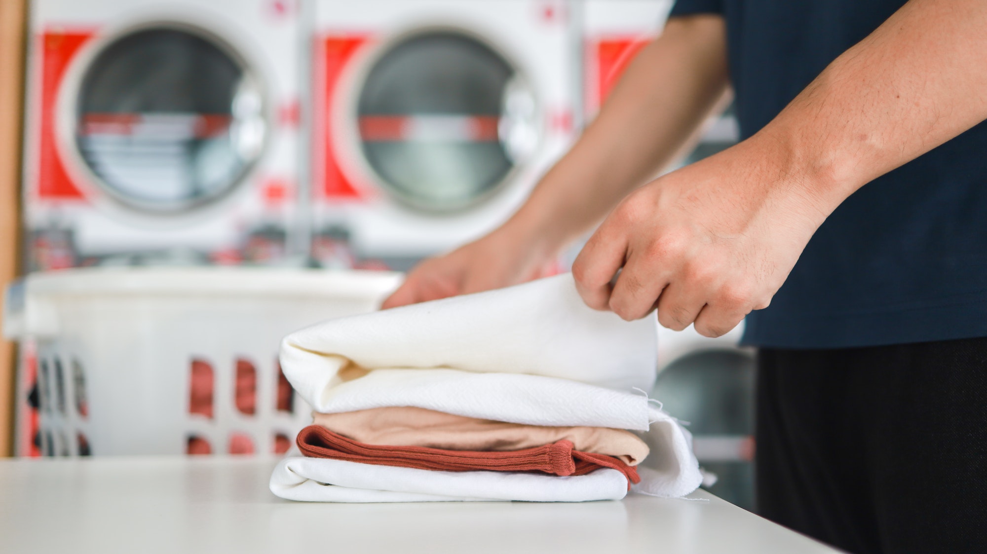 Man doing launder holding basket with dirty laundry of the washing machine in the public store.